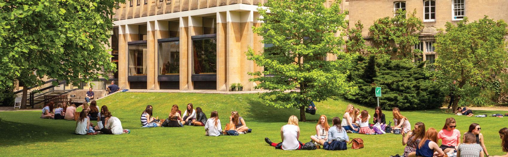 Community college students sitting in the grass in front of a building