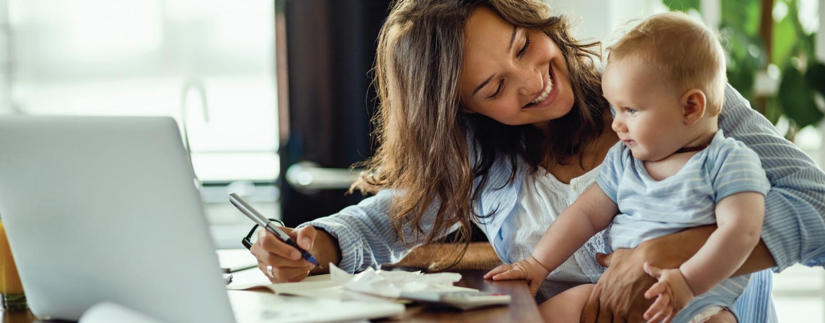 mother holding child and smiling while working