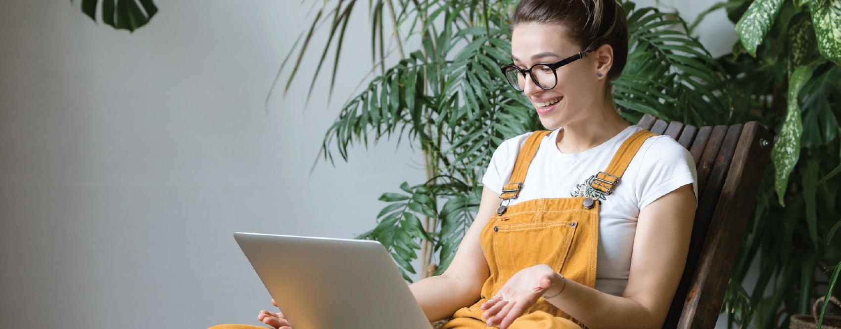 woman working on a laptop with a plant