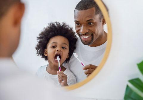 father and child brushing teeth